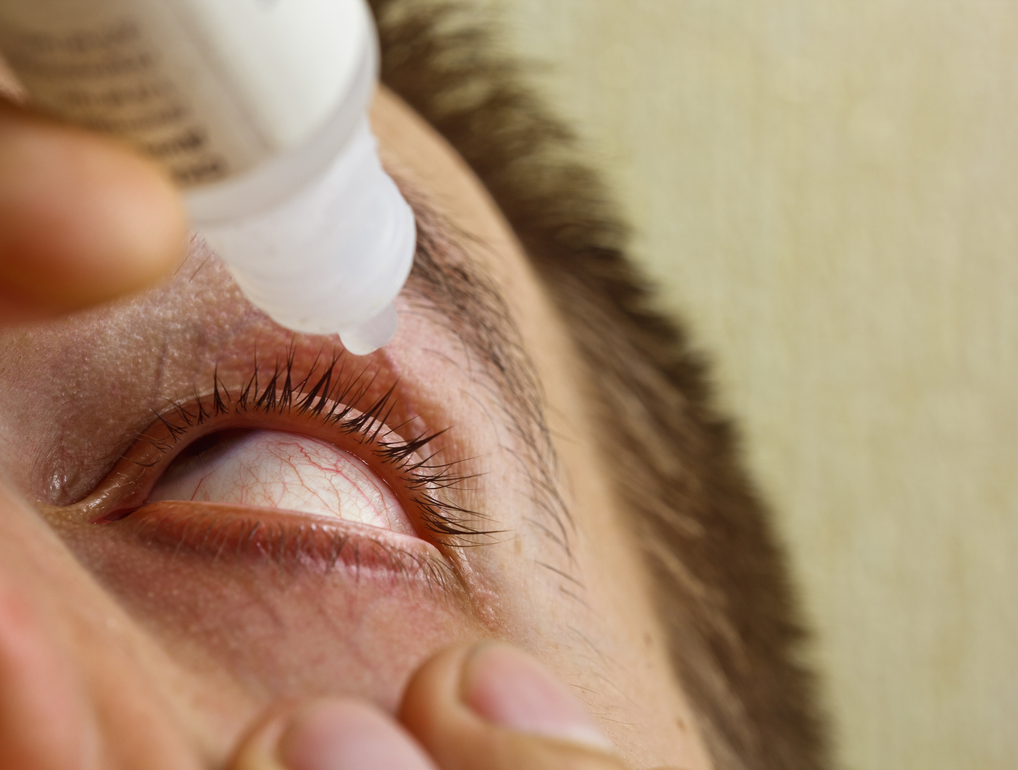 close up of a man putting eye drops in his eye