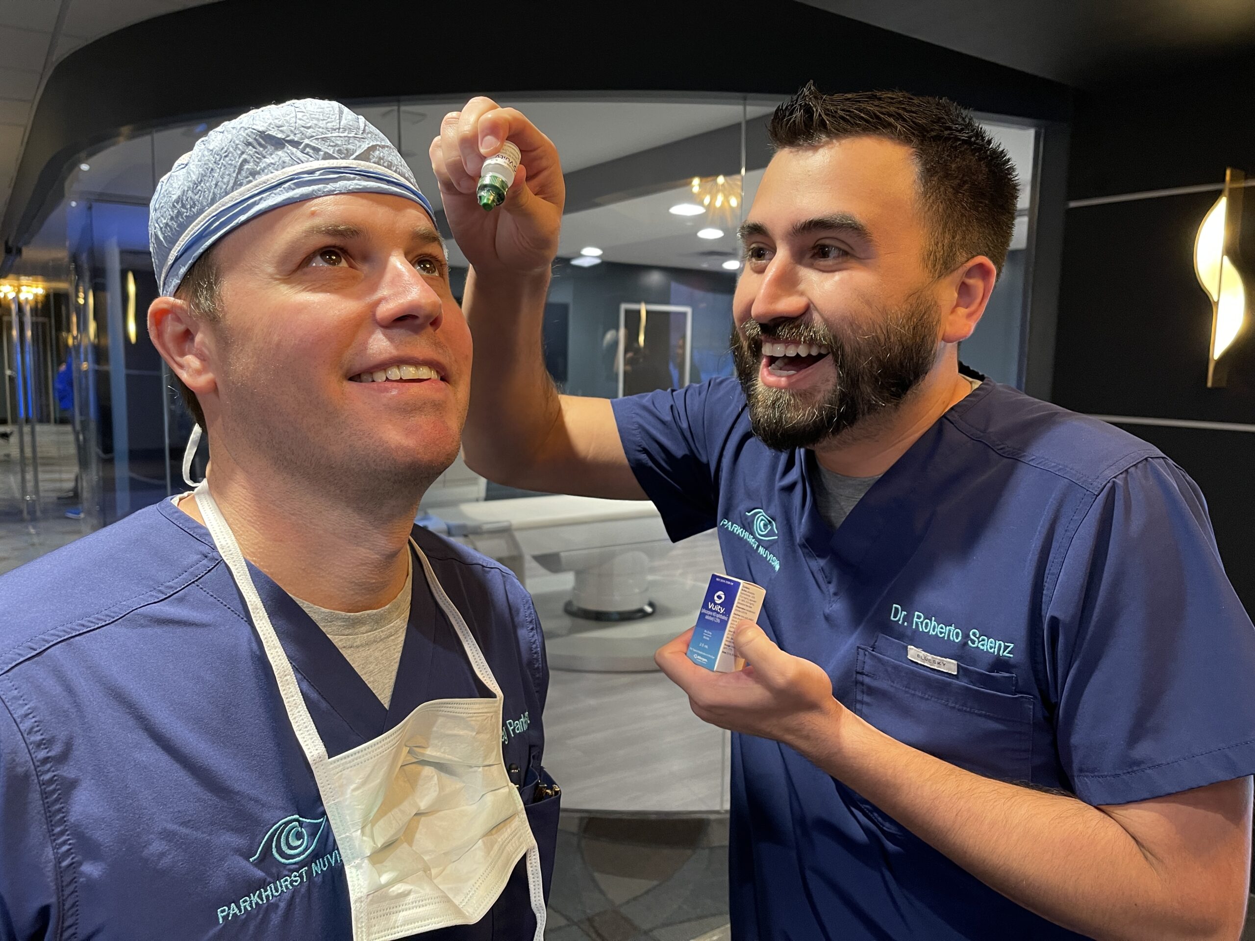 a doctor putting eye drops in another doctors eye.