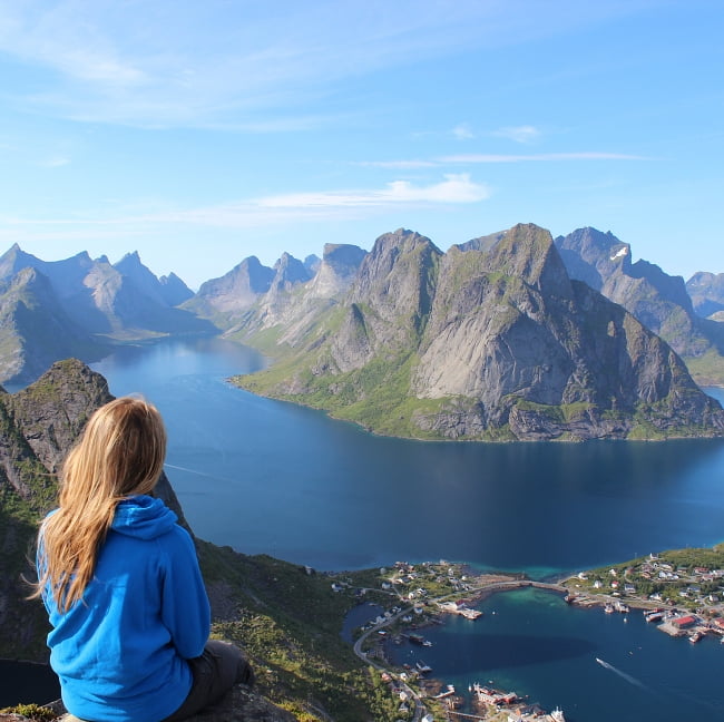 woman sitting on cliffside overlooking an incredible mountain lake
