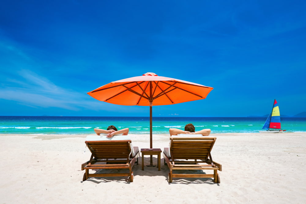 Two people relaxing on a white sandy beach