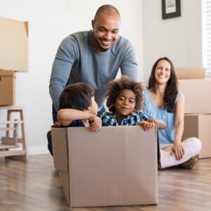 Black family playing with children in carboard boxes while moving