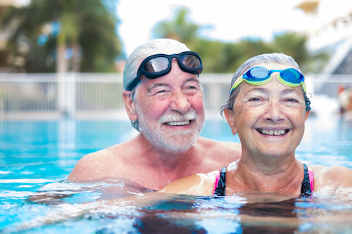 elderly couple swimming and smiling with fixed vision