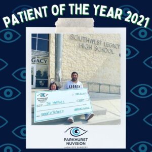 dad and daughter sitting in front of a school with a large check in their laps. Parkhurst nuvision's patient of the year 2021