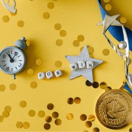 confetti on yellow table, with award and alarm clock